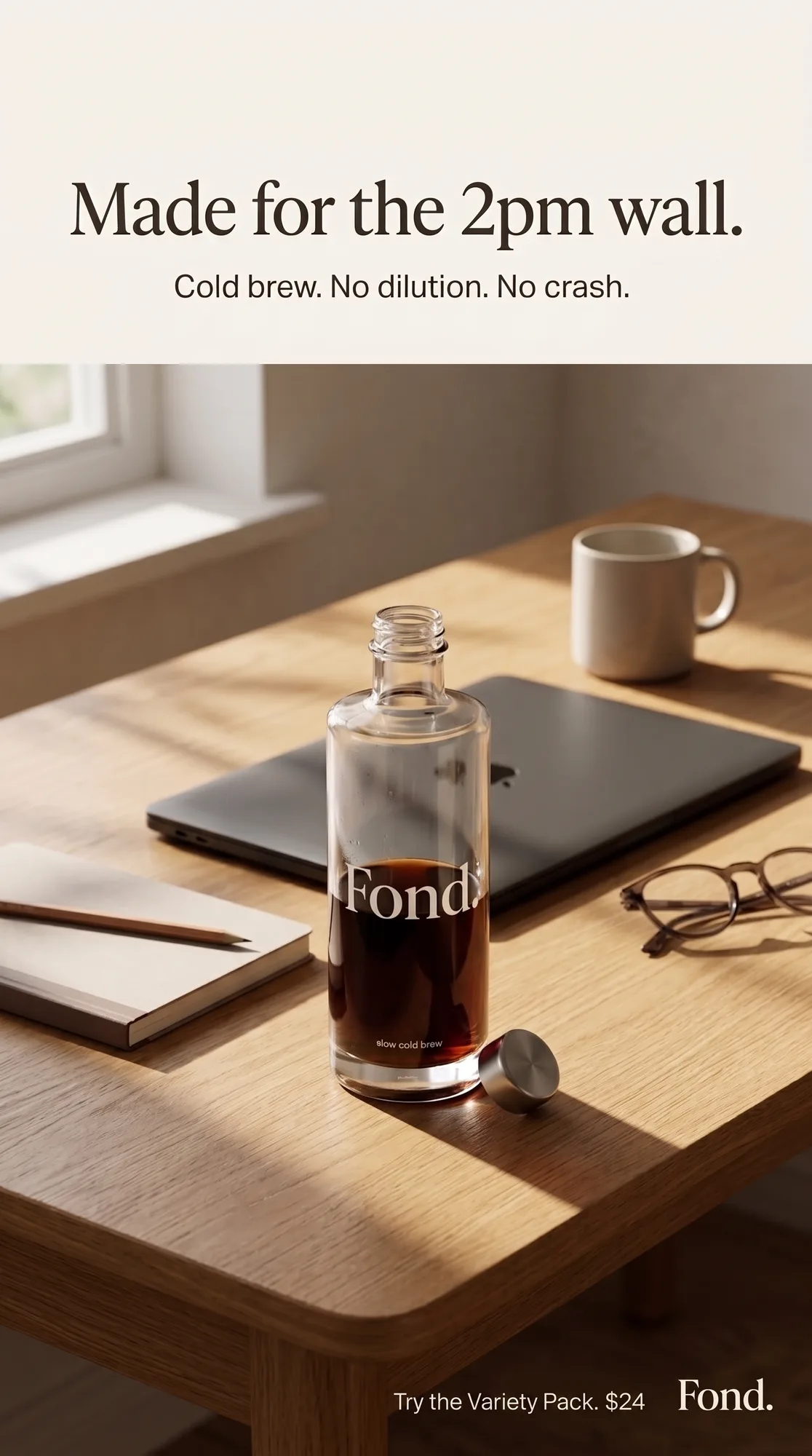 Fond. — bottle on a wooden work desk with laptop, glasses, and notebook in warm afternoon light, 'Made for the 2pm wall'